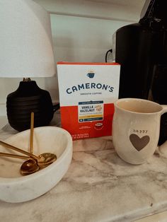 two coffee mugs sitting on top of a counter next to a box of cameron's coffee