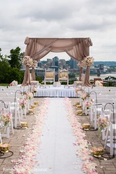 an outdoor ceremony setup with white chairs and pink flowers on the aisle, overlooking a cityscape