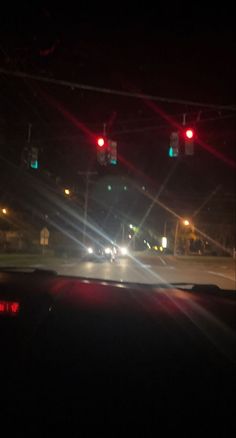 the view from inside a car at night with street lights and cars driving down the road