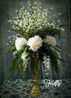 white flowers and greenery in a gold vase