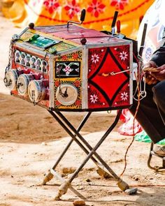 a man sitting in front of an old fashioned radio on a stand with wheels and knobs