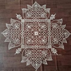 an intricately designed design is shown on a wooden table top, with white ink in the center