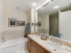 a bathroom with two sinks and a bathtub next to a large mirror on the wall