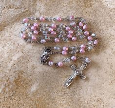 This is a beautiful Catholic rosary I made in the traditional five-decade design. This rosary makes a unique and thoughtful gift to treasure. The total length is 19 1/2 inches and it feels great in the hand. ** FREE SHIPPING FOR THIS ROSARY** Beads: I alternated crystal beads in frosted cotton-candy pink with iridescent-clear crystal beads for the 53 Hail Marys. I used precious rose-inside in pink for the six Our Father beads. Medals: I used a rose motif Crucifix that is 1 1/2 inches and the Our Lady of Grace centerpiece is 3/4 inches. Both medals were made of base metal in Italy. *Free Gift Packaging: This rosary comes in a royal-blue velour keepsake bag and gift box. *Care Tip: Over time, and with use, the medals may develop a patina. If you prefer to bring back the shine, simply rub the Spiritual Cross Rosary With Faceted Beads, Faceted Beads Crucifix Rosary As Gift, Silver Hand-strung Rosary As Gift, Spiritual Rosary For First Communion, Custom Rosary, Pink Cotton Candy, Rosary Catholic, Rosary Beads, Green Crystals