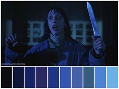 a woman holding a knife in the dark with color swatches on her face and hands