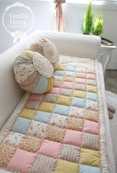 a crocheted blanket is laying on top of a white couch next to a potted plant