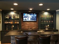 a bar with stools in front of it and a television mounted on the wall