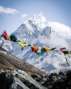 there are many colorful flags hanging on the mountain