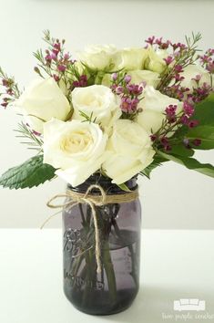 a bouquet of white roses in a mason jar