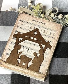 a christmas nativity scene is displayed on a tablecloth with holly and pine branches