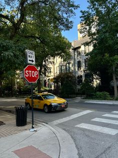 a red stop sign sitting on the side of a road next to a trash can