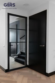 an open door leading to a staircase in a room with wooden floors and white walls