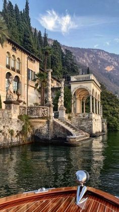 a boat traveling down a river next to a large building with columns on the side