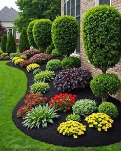 a garden with flowers and bushes in front of a house