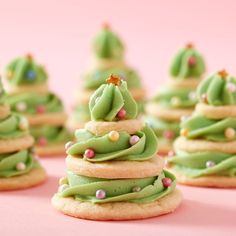 green frosted christmas tree cookies on a pink surface with other decorated cookies in the background