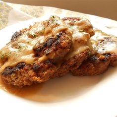 two meat patties covered in gravy on a plate