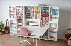 a room with a desk, chair and bookcase full of crafting supplies in it