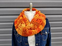 an orange and yellow crocheted scarf hanging from a mannequin's dummy