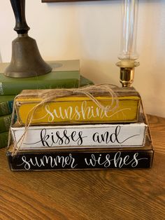 three wooden signs that say sunshine, kisses and summer wishes sitting on top of books