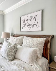 a bed with white linens and pillows in a bedroom next to a framed sign that says it's well with my soul