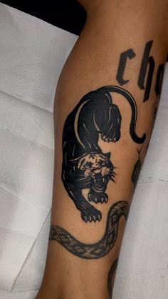 a tattoo on the leg of a person with a cat and snake in its claws