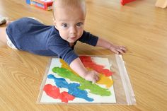 a baby laying on the floor playing with some paint