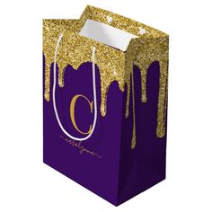 a purple and gold gift bag with the letter c on it's front side