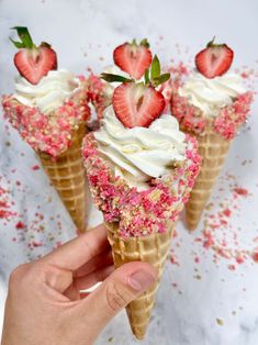 three ice cream cones with strawberries on top and sprinkles all over them