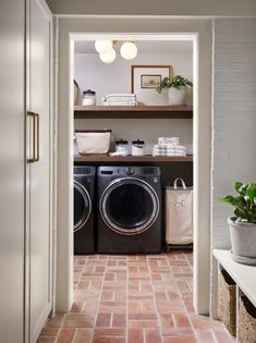 a washer and dryer sitting in a room next to a shelf with plants