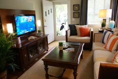 a living room filled with furniture and a flat screen tv on top of a wooden table