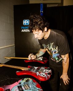 a young man is playing with his red guitar