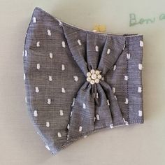 a gray and white polka dot purse with a bow at the front on a table