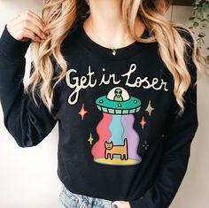 Alien Love UFO Sweatshirt, Retro UFO Jumper, Harajuku Groovy Space Sweater, Positive Quote Crewneck, Trendy Planets School Sweatshirt UNISEX Who can resist this aesthetic Space UFO Sweatshirt? It's comfy and soft make makes a perfect gift for a loved one, or for anyone who is a fan of the extraterrestrial or space. The quote on the jumper reads 'Get in loser'. The cute jumper and available in multiple colours and sizes. *MADE TO ORDER ITEM*   - - FEATURES - - - 50% cotton, 50% polyester - Medium Retro Long Sleeve Top With Funny Print, Fun Long Sleeve Slogan Tops, Retro Winter Tops With Cartoon Print, Space Sweater, Alien Love, Cute Jumpers, School Sweatshirts, Aesthetic Space, Positive Quote