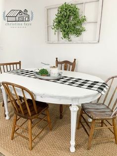 a dining table with four chairs and a checkered table cloth on it in front of a window