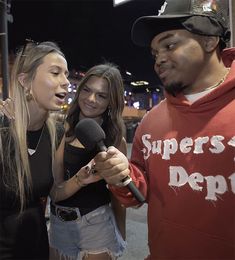 two girls and a man are talking to each other while holding a microphone in front of them