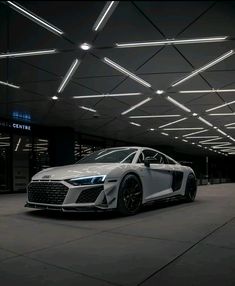 a white car parked in front of a building with lights on it's ceiling