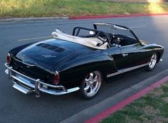 an old black car parked on the side of the road with its top down and it's hood up