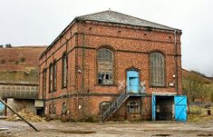 an old red brick building with blue doors and steps leading up to the second floor