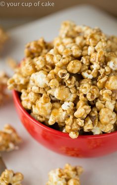 a red bowl filled with caramel popcorn on top of a white counter next to other items