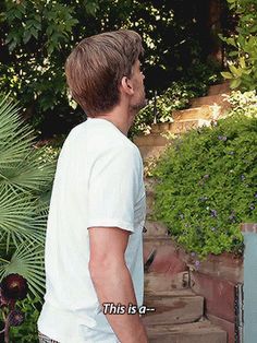 a man standing in front of a green plant with the words this is a written on it