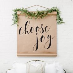 a canvas sign that says choose joy hanging on a wall above a bed with pillows