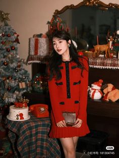 a woman standing in front of a christmas tree with presents on the table behind her