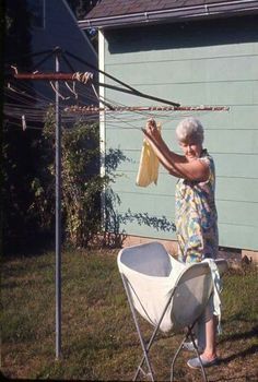 an old woman is drying clothes outside in the yard