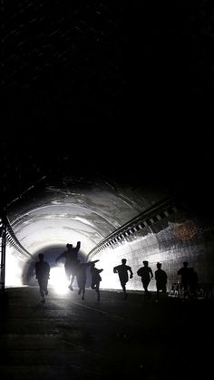 silhouettes of people walking through a tunnel at night