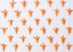 many small orange birds on a white surface