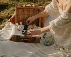 a woman is sitting on the grass near a basket