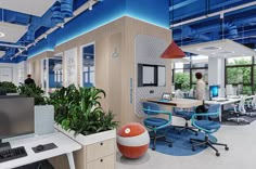 an office with blue and white walls, desks, computers and people in the background