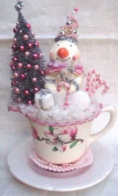 a snowman in a teacup with candy canes and christmas trees on top