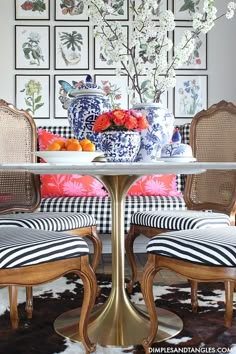 the dining room table is decorated with blue and white vases, red flowers, and striped chairs