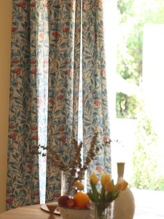 a vase filled with flowers sitting on top of a wooden table next to a window